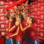 persona con bandera de fútbol junto a las figuras de la selección española de futbol